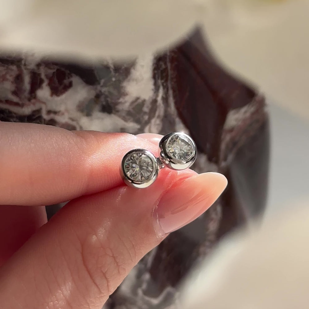 
                      
                        Load and play video in Gallery viewer, The Vera Earrings - 5mm (0.5ct - 1cttw) Moissanite Round Bezel Studs
                      
                    